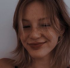 a woman with freckled hair smiling at the camera while wearing a black top