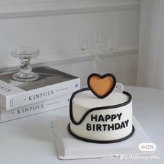 a birthday cake sitting on top of a table next to two books and a candle