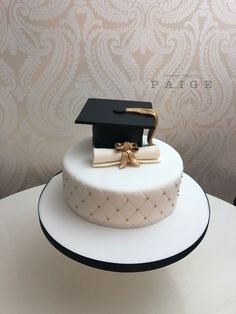 a white cake with a black graduation hat and diploma on top, sitting on a table