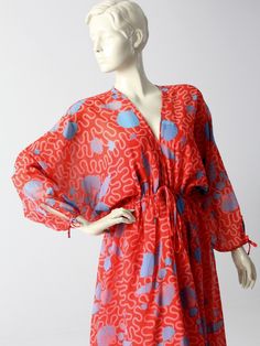 "1970s A rare find! This vintage dress was from an early Zandra Rhodes collection. The airy, faux chiffon red dress features a blue and pink seashell print. Bat wing sleeves and a full skirt add to the dramatic flair of the maxi dress. The elasticized waist is detailed with a decorative bow tie. ○ Airy, faux silk chiffon (polyester) dress ○ Bold red dress with a sky blue and pink seashell print. ○ Bat wing sleeves with keyhole tie sleeve ends ○ Elasticized empire waist with a decorative bow tie Red Long Sleeve Dress For Beach Cover-up, Red Long Sleeve Maxi Dress For Beach Cover-up, Red Flowy Dress With Kimono Sleeves, Red Kimono Sleeve Beach Dress, Red Beachwear Dress With Kimono Sleeves, Retro Flowy Beach Dress, Flowy Vintage Maxi Dress For Beach, Retro Red Beach Dress, Red Dress With Kimono Sleeves For Beach