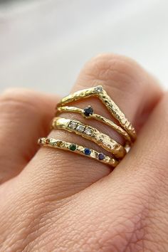 a woman's hand with three different rings on her finger and one is holding the other