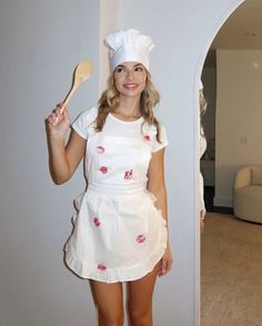 a woman in a chef's outfit holding a wooden spoon and posing for the camera