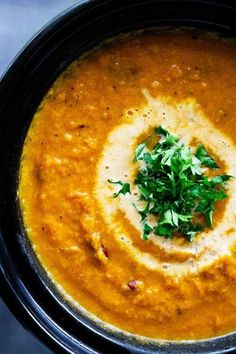 a black bowl filled with soup and garnished with parsley on the top