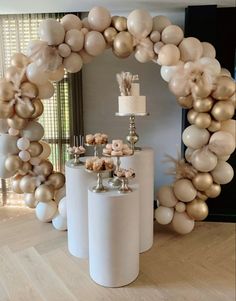 an arch made out of balloons and some desserts on top of the table in front of a window