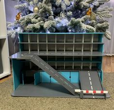 a toy train set sitting on top of a shelf in front of a christmas tree