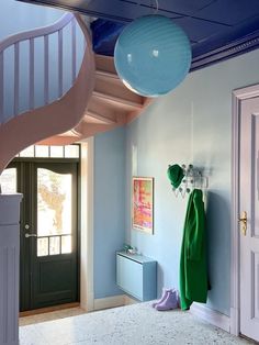 a room with blue walls and white floors, two green umbrellas hanging from the ceiling