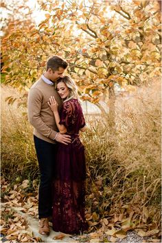 a man and woman standing next to each other in the leaves