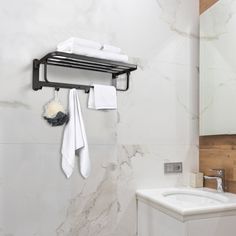 a white toilet sitting next to a bathroom sink under a mirror and towel rack on the wall