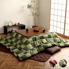 a living room filled with furniture next to a wooden floor covered in green and brown blankets