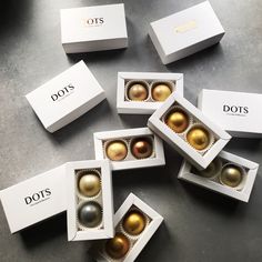 six different types of chocolates in white boxes on a table with gold and silver ornaments