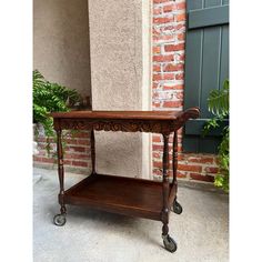 an old wooden table sitting in front of a brick wall next to a planter