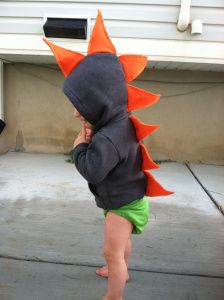 a toddler wearing an orange and black dinosaur hoodie