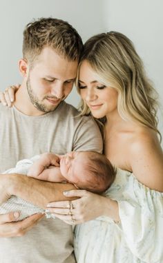 a man and woman holding a baby in their arms