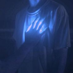 a man holding a cell phone in his hand with blue light coming from behind him