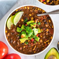 two bowls filled with beans, avocado and tomatoes on top of a white table