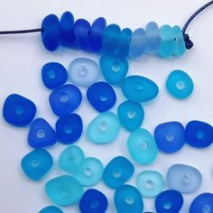 blue glass beads are laid out on a white surface with a string attached to it