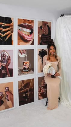 a woman standing in front of a wall with pictures on it and holding a bouquet