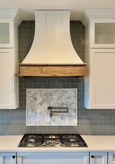 a stove top oven sitting inside of a kitchen next to white cabinets and counter tops