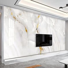 a living room with white marble walls and a flat screen tv mounted on the wall