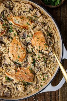 chicken and mushroom pasta in a skillet with a gold serving spoon on the side