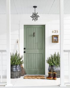 the front door is painted green and has two potted plants