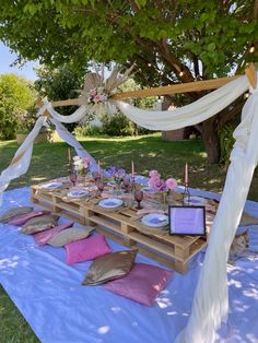 an outdoor table set up with plates and napkins