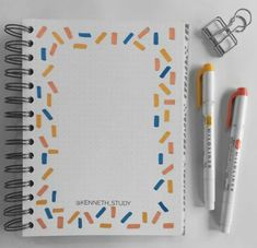 an open notebook with markers and pens next to it