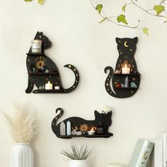 three black cats are on shelves with candles