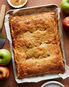 an apple pie sitting on top of a pan next to some apples and a knife