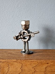 a small metal object sitting on top of a wooden table next to a blue wall