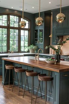 a kitchen with green cabinets and wooden counter tops in front of two large windowed windows