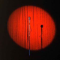 a microphone is shown in the middle of a dark room with red light coming from behind it