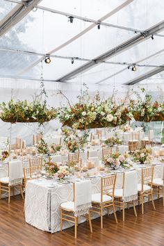 the tables are set up with white linens and floral centerpieces, along with hanging flower arrangements