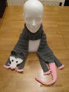 a white mannequin head wearing a gray and pink knitted scarf with a mouse on it