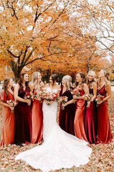 a group of women standing next to each other in front of trees with leaves on the ground