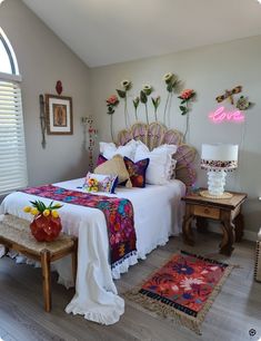 a bedroom with a bed, table and rugs on the floor in front of it