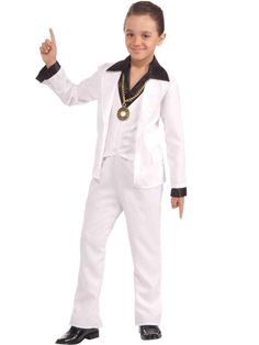 a young boy dressed in white and black is posing for the camera with his finger up