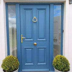 a blue front door with two potted plants