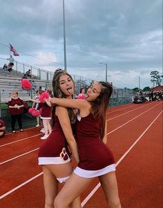 two cheerleaders hugging each other on a track