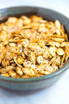 a bowl filled with pumpkin seeds on top of a table