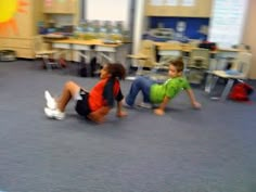 two children are playing on the floor in a classroom