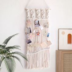 a macrame hanging on the wall with pictures and magnets attached to it