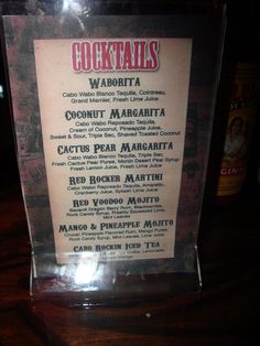 the menu for cocktails is displayed in a clear case on a table top with other items