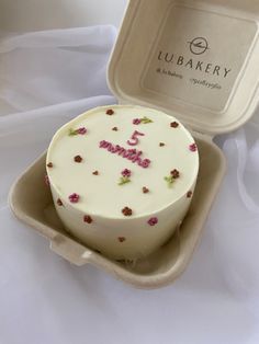 a white cake in a box with pink and green flowers on it's side