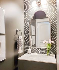 a white sink sitting under a bathroom mirror next to a wall mounted faucet