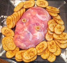 a platter with crackers, cheese and ham in the shape of a face