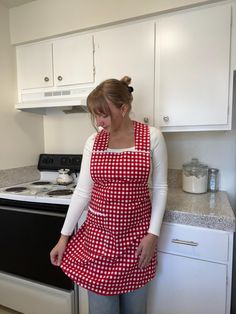 a woman wearing an apron standing in front of a stove