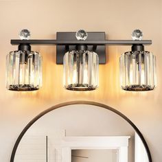 a bathroom vanity light with three lights on the wall above it and a mirror in front of it