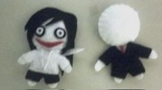 two stuffed dolls are sitting next to each other on a table, one is black and the other is white