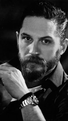 a black and white photo of a man with a watch on his left hand, wearing a suit